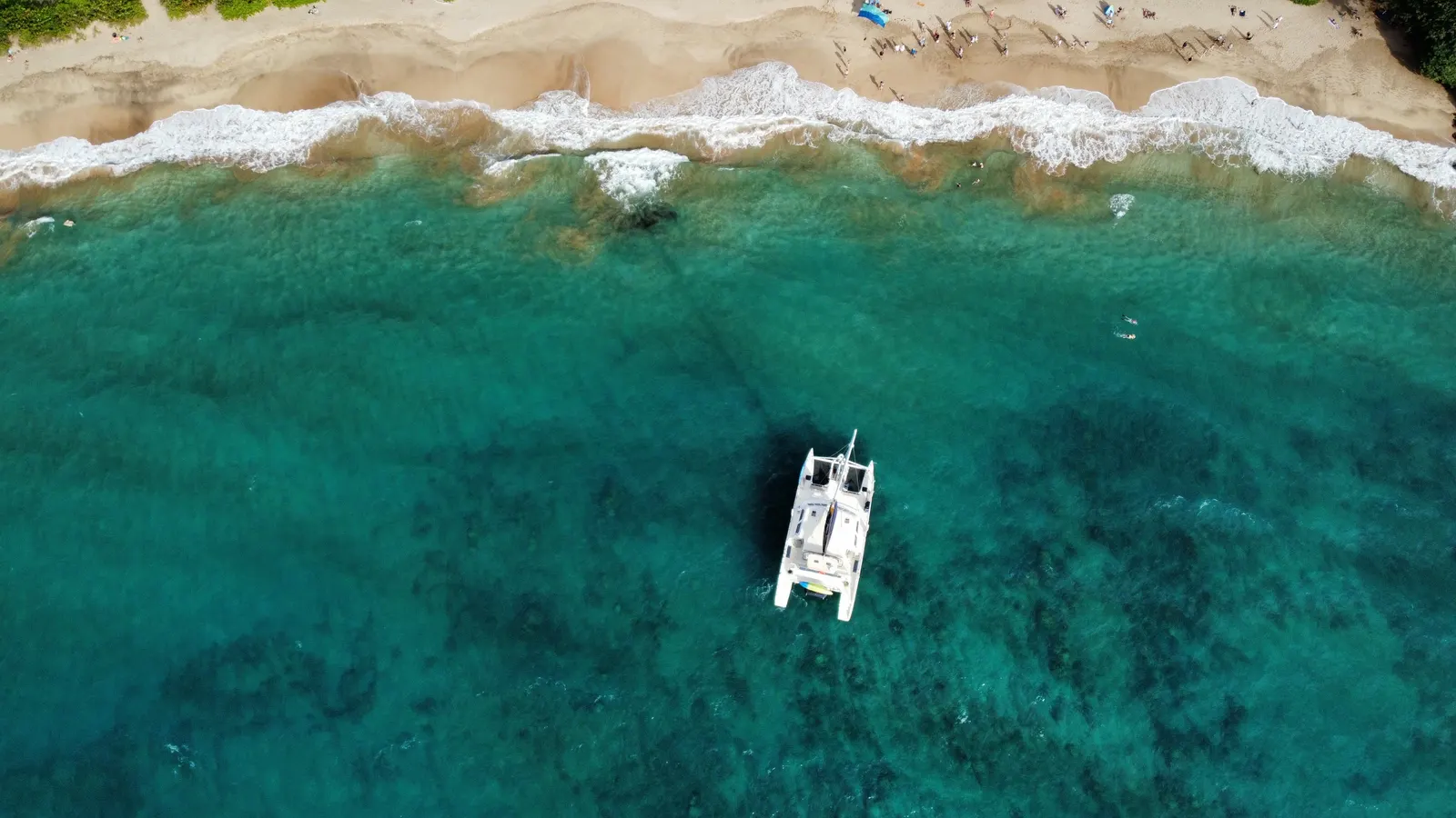 Catamaran au mouillage devant une plage, vue aérienne verticale